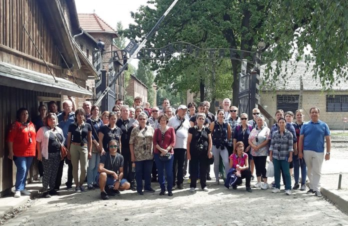 A tanulmányút résztvevői az auschwitzi koncentrációstábor bejáratánál, ahol a kapu fölött ez a felirat fogadja az érkezőt ’Arbeit macht frei – A munka szabaddá tesz’