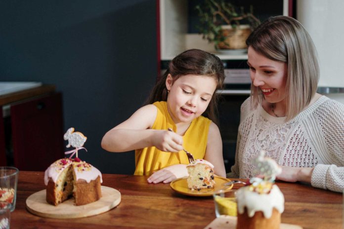 mom-and-daughter-eating-cake-on-brown-wooden-table-3992140